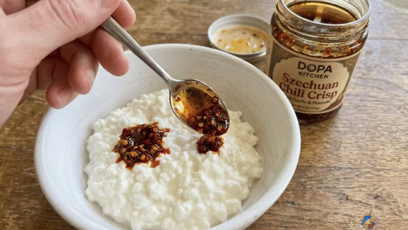 spooning chili crisp over cottage cheese in a bowl